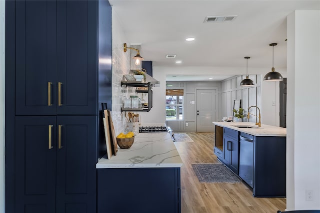 kitchen with blue cabinetry, light hardwood / wood-style flooring, stainless steel dishwasher, and sink