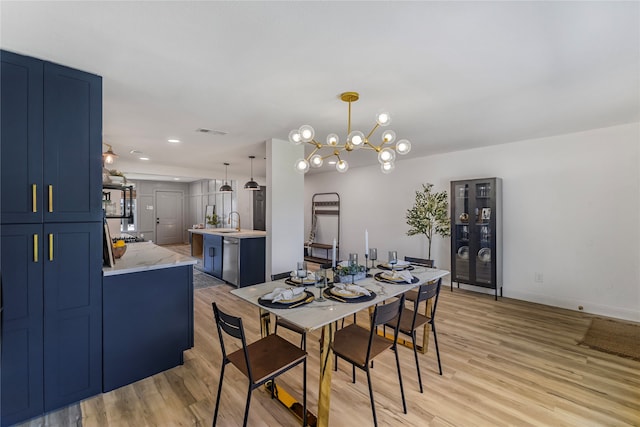 dining space featuring a chandelier, sink, and light hardwood / wood-style floors