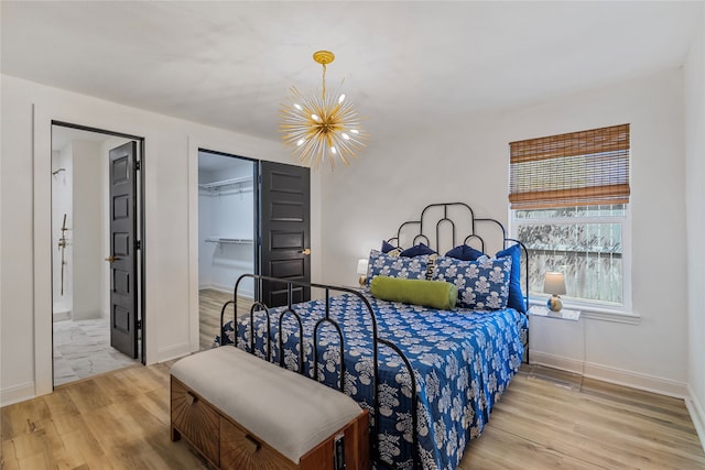 bedroom featuring light hardwood / wood-style flooring, an inviting chandelier, a spacious closet, and a closet