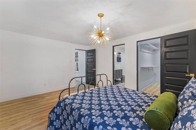 bedroom featuring light wood-type flooring, an inviting chandelier, a spacious closet, and a closet