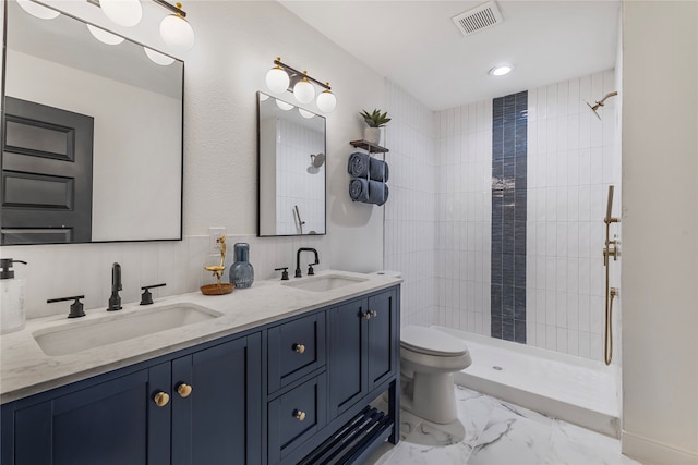 bathroom featuring tiled shower, toilet, and vanity