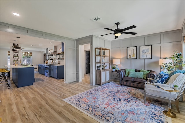 living room with ceiling fan, sink, and light hardwood / wood-style flooring