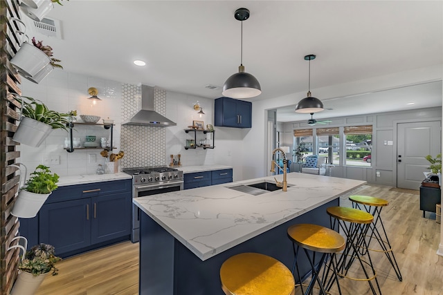 kitchen featuring light wood-type flooring, stainless steel range with gas cooktop, sink, and wall chimney exhaust hood