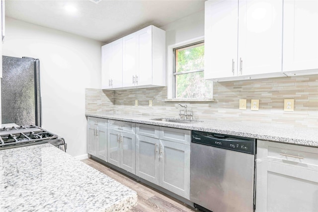 kitchen with appliances with stainless steel finishes, sink, decorative backsplash, white cabinetry, and light wood-type flooring