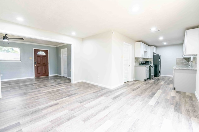 unfurnished living room with ceiling fan, light hardwood / wood-style floors, crown molding, and sink