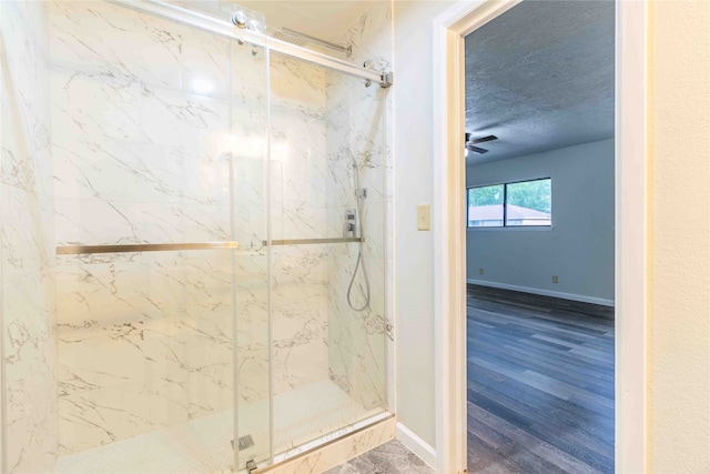 bathroom with a textured ceiling, hardwood / wood-style flooring, a shower with shower door, and ceiling fan