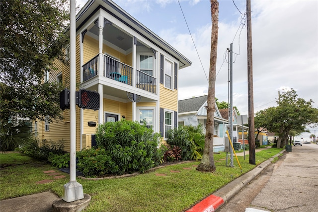 exterior space featuring a balcony and a front yard