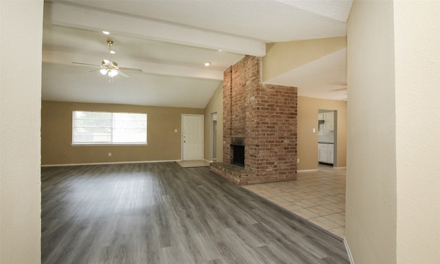 unfurnished living room with a fireplace, lofted ceiling with beams, light hardwood / wood-style floors, ceiling fan, and a textured ceiling