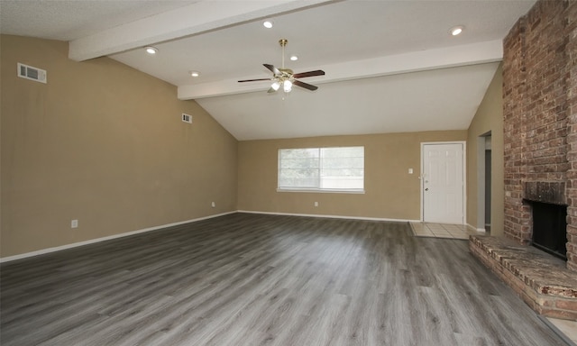 unfurnished living room with ceiling fan, vaulted ceiling with beams, wood-type flooring, and a brick fireplace