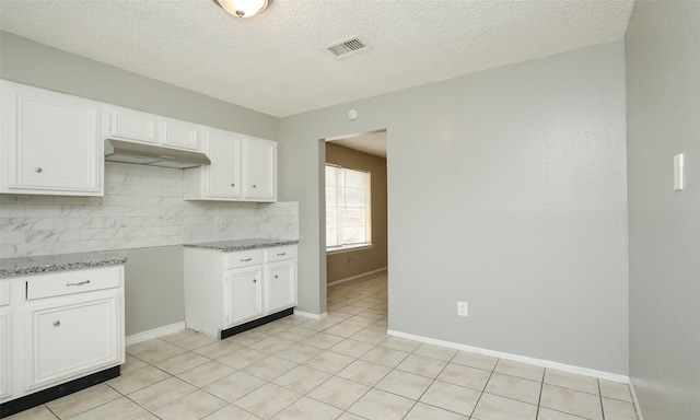 kitchen featuring light stone counters, decorative backsplash, white cabinetry, and a textured ceiling