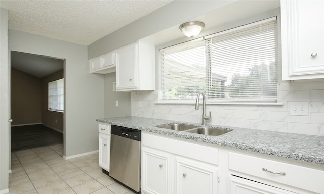 kitchen with a textured ceiling, stainless steel dishwasher, sink, white cabinetry, and light stone counters