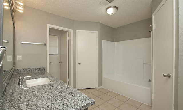 bathroom with tile patterned flooring,  shower combination, a textured ceiling, and vanity