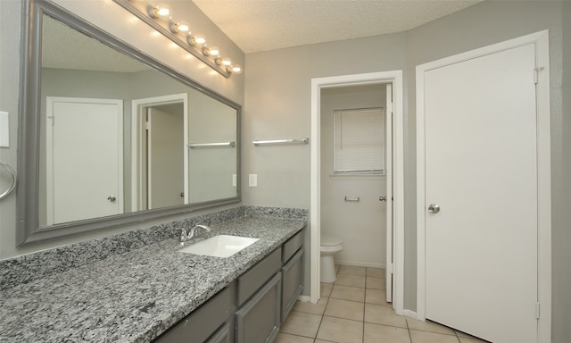 bathroom with a textured ceiling, vanity, toilet, and tile patterned floors