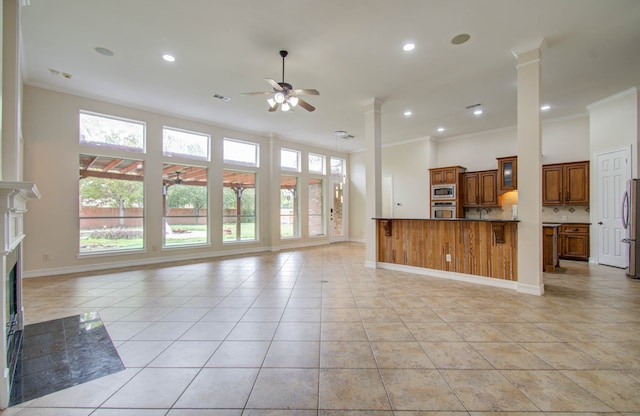 unfurnished living room with crown molding, ornate columns, light tile patterned floors, and ceiling fan