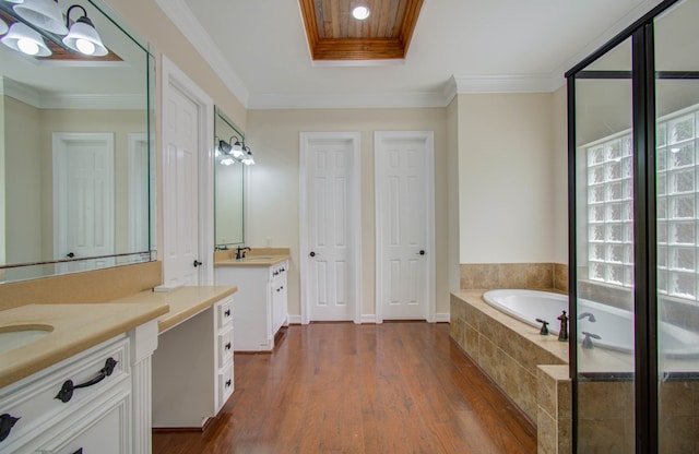 bathroom featuring vanity, a relaxing tiled tub, hardwood / wood-style flooring, and crown molding