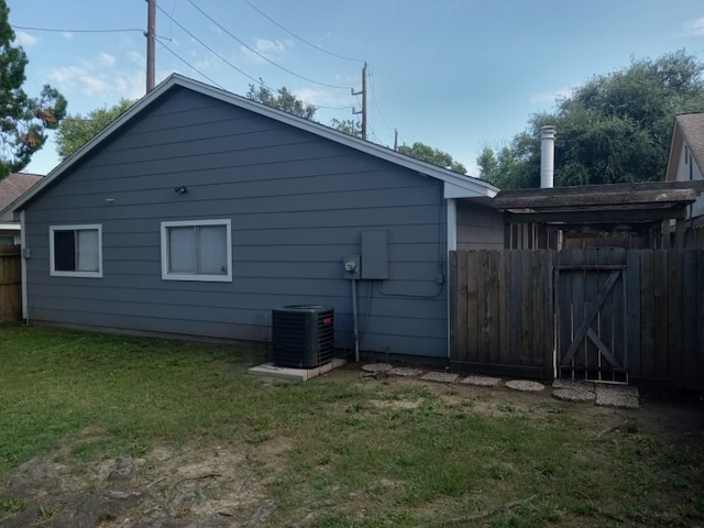 back of house with cooling unit and a lawn