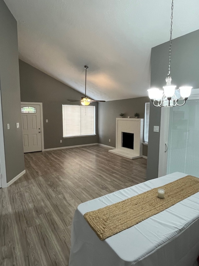 living room featuring lofted ceiling, ceiling fan with notable chandelier, and dark hardwood / wood-style floors