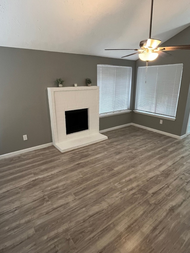 unfurnished living room with ceiling fan, dark hardwood / wood-style floors, and a brick fireplace