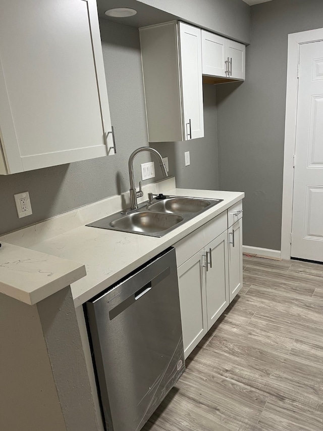 kitchen with white cabinets, light wood-type flooring, stainless steel dishwasher, and sink