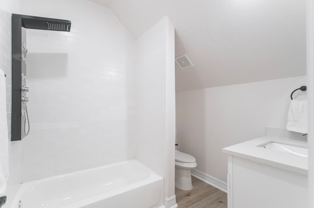 full bathroom with hardwood / wood-style flooring, vaulted ceiling, tiled shower / bath combo, vanity, and toilet