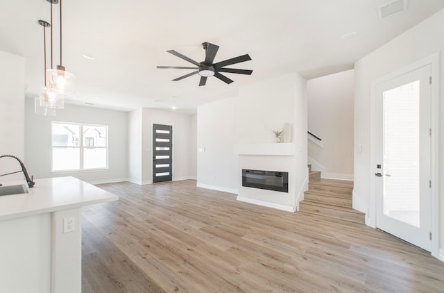 unfurnished living room featuring ceiling fan, light hardwood / wood-style flooring, and sink