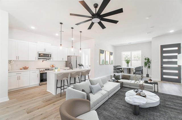 living room featuring ceiling fan and light hardwood / wood-style flooring