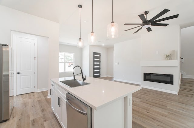 kitchen with an island with sink, hanging light fixtures, sink, white cabinetry, and appliances with stainless steel finishes