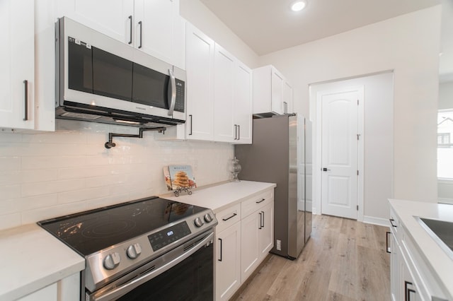 kitchen with stainless steel appliances, white cabinets, light wood-type flooring, and backsplash