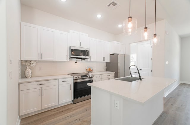 kitchen with decorative light fixtures, stainless steel appliances, and white cabinetry