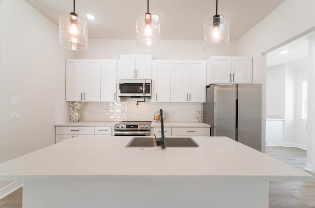 kitchen featuring stainless steel appliances, white cabinetry, and hanging light fixtures