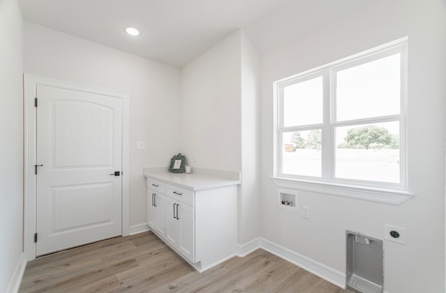 clothes washing area with washer hookup, cabinets, light hardwood / wood-style floors, and electric dryer hookup