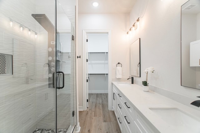 bathroom with wood-type flooring, a shower with door, and vanity