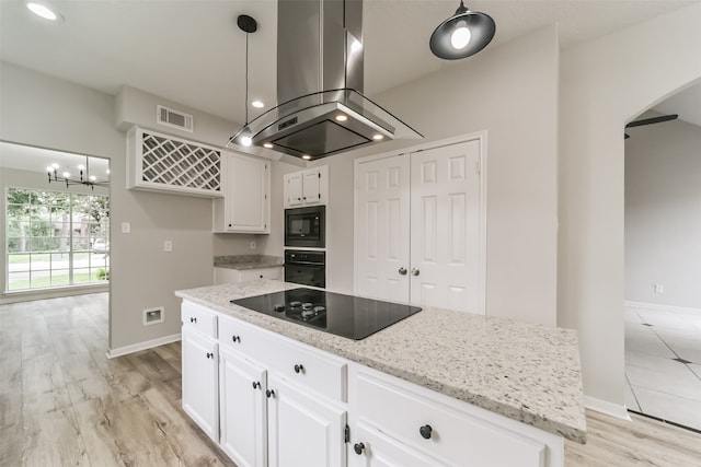 kitchen featuring white cabinetry, decorative light fixtures, black appliances, a center island, and island exhaust hood