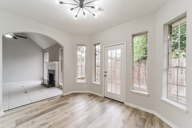 entryway with vaulted ceiling, a textured ceiling, ceiling fan, and light hardwood / wood-style floors