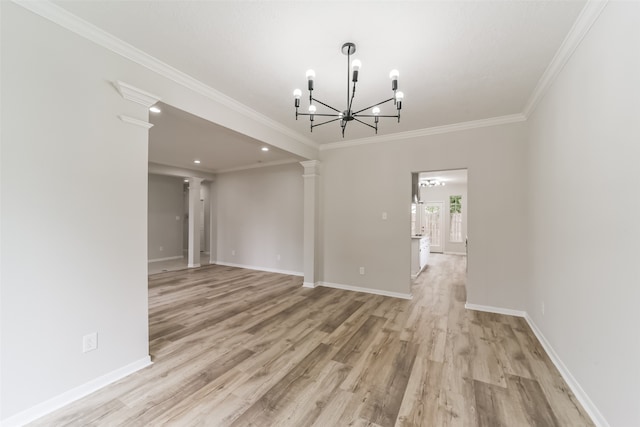 spare room featuring ornamental molding, an inviting chandelier, decorative columns, and light hardwood / wood-style floors