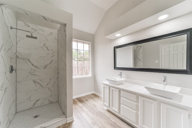 bathroom featuring vaulted ceiling, hardwood / wood-style flooring, tiled shower, and vanity