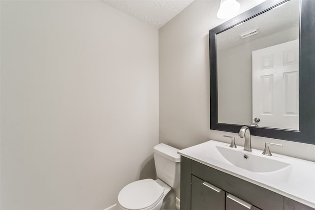 bathroom featuring a textured ceiling, vanity, and toilet