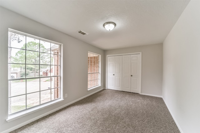 unfurnished bedroom featuring a closet, a textured ceiling, and carpet