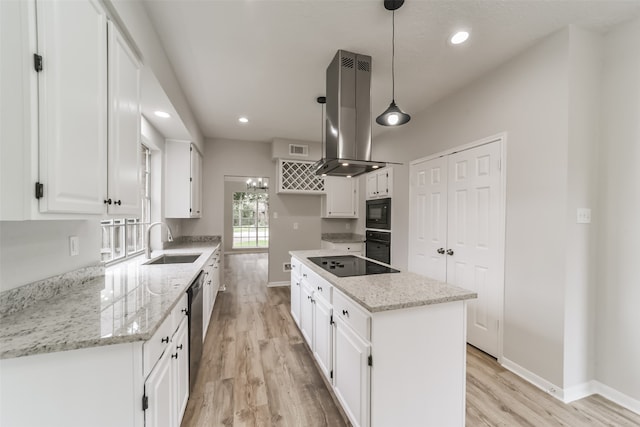 kitchen featuring hanging light fixtures, sink, light stone countertops, and white cabinets