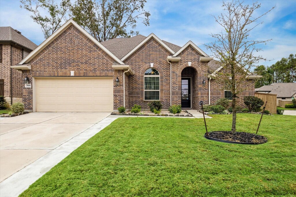7906 Summit Trail Ln, Porter, TX 77365 - view of front facade with brick siding, an attached garage, concrete driveway, and a front yard