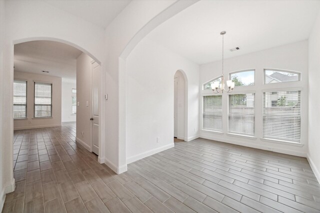 spare room featuring hardwood / wood-style floors and a chandelier