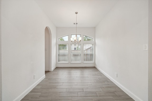 unfurnished dining area with wood-type flooring and a chandelier