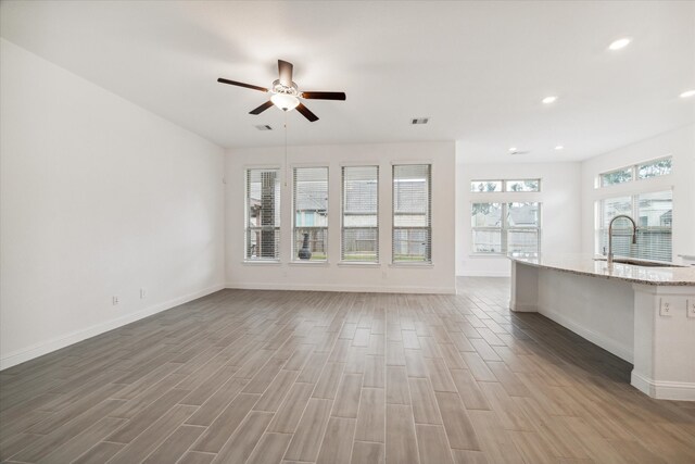 unfurnished living room with ceiling fan, light hardwood / wood-style floors, and sink