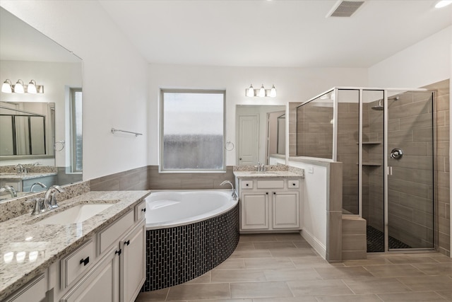 bathroom featuring vanity and independent shower and bath