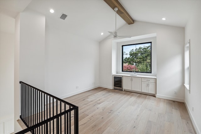 interior space with light wood-type flooring, lofted ceiling with beams, ceiling fan, and wine cooler