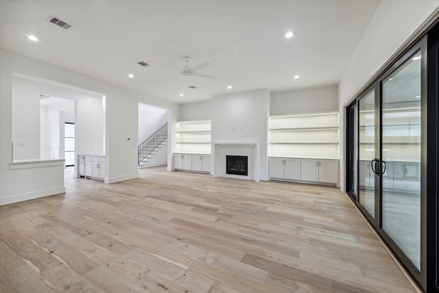 unfurnished living room featuring light wood-type flooring, ceiling fan, and plenty of natural light