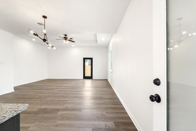 empty room with ceiling fan with notable chandelier and hardwood / wood-style flooring