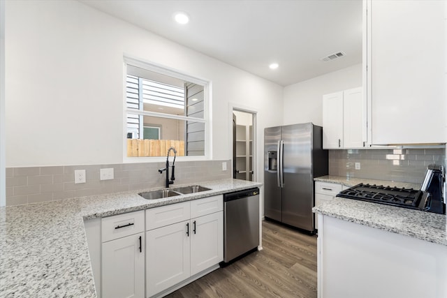 kitchen featuring white cabinets, light wood-type flooring, appliances with stainless steel finishes, light stone counters, and sink