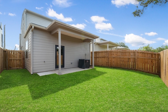 rear view of house with cooling unit, a yard, and a patio area