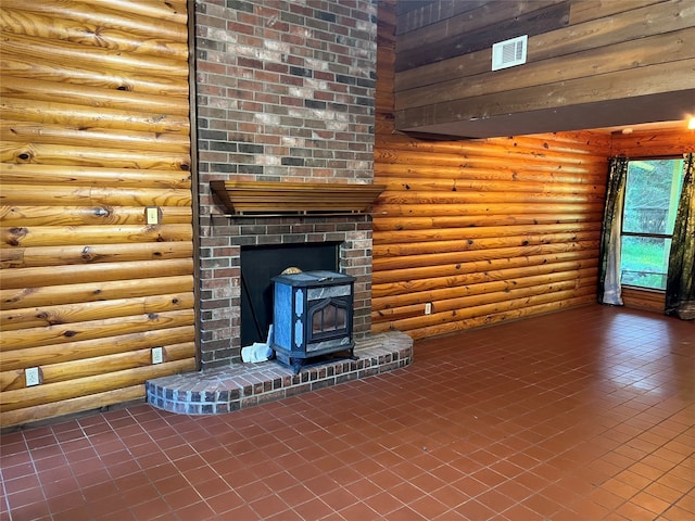 unfurnished living room featuring log walls, a wood stove, and tile patterned flooring